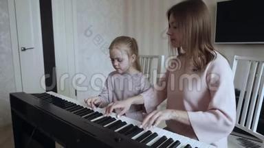 年轻的老师和小可爱的女孩在电动<strong>钢琴</strong>上演奏。